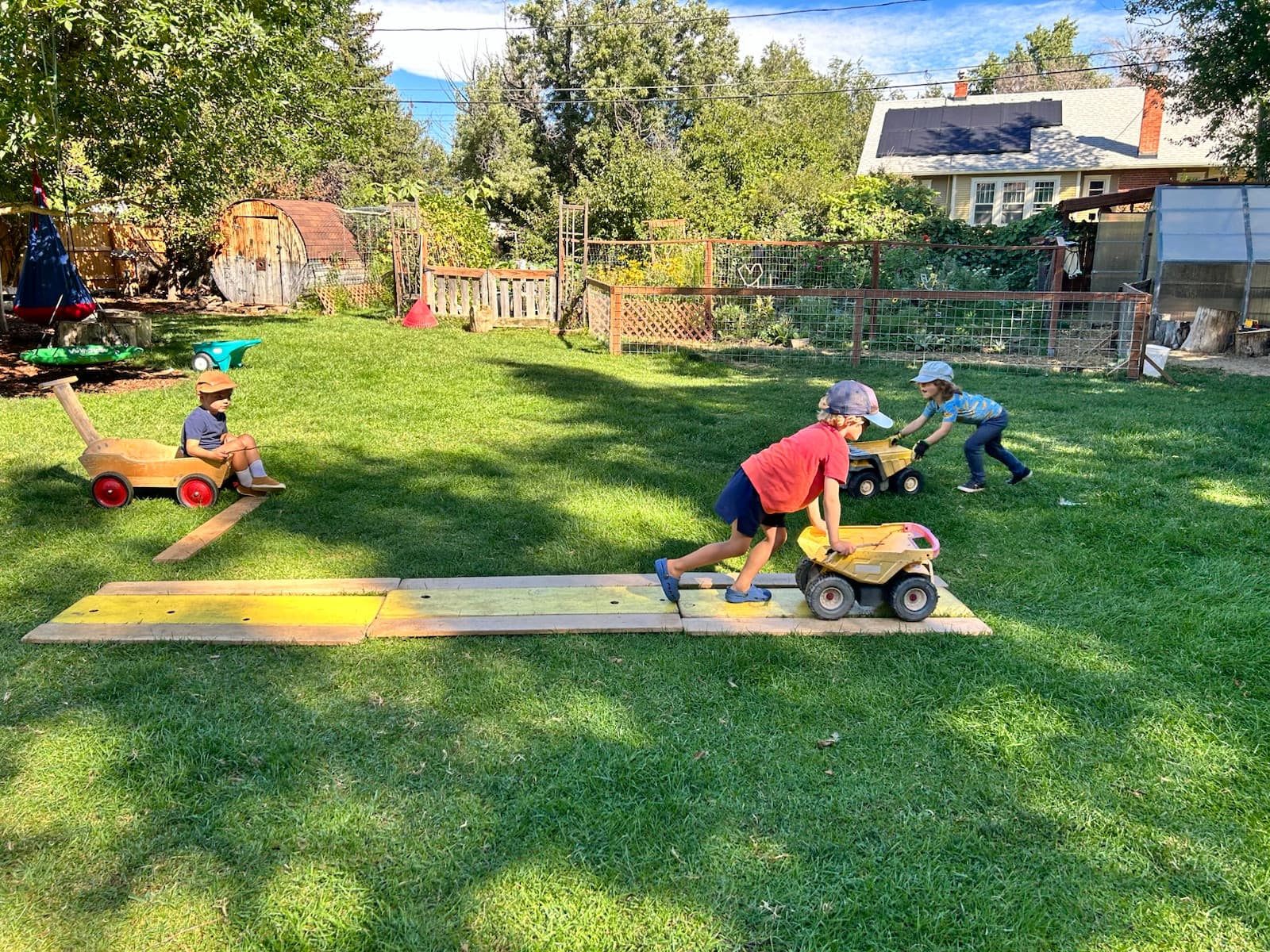 Ride-on trucks racing down the plank ramp across the lawn