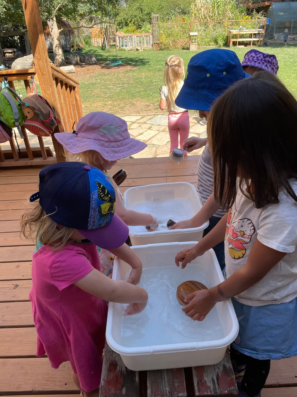 Campers splashing at the water tables on the sunny deck